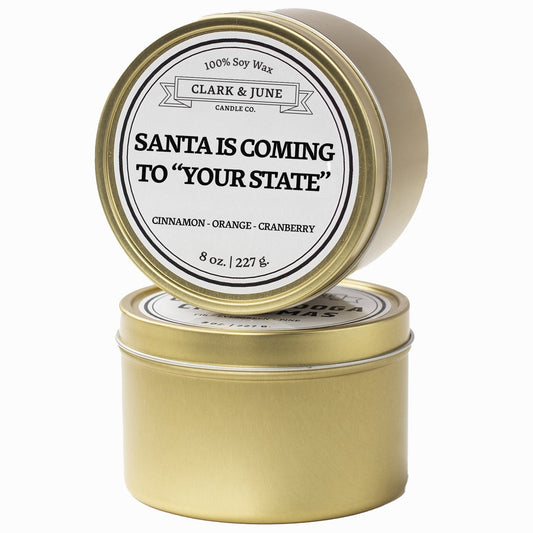 Single wicked Cinnamon - Orange - Cranberry  scented 8oz candle in gold finish with Santa is Coming to "Your State" on the label. SEO Text –soy wax candle, Christmas candle, Holiday candle hand poured, small batch, scented candle, Woman Owned, local candle, Housewarming present, gives back, charity, community candle, Soy wax candle Christmas gift.
