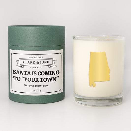 Double wicked soy candle in a 13.5 oz tumbler with the state of   Alabama printed in 22k gold foil on the face. Green cylinder packaging with Santa is Coming to "Your Town" on the label. SEO Text â€“ Drinking glass, soy wax candle, Christmas Candle, hand poured, small batch, scented candle, Woman Owned, local candle, Housewarming present, gives back, charity, community candle, becomes a cocktail glass, closing gift. 
