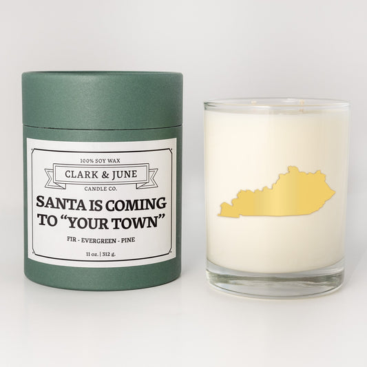 Double wicked soy candle in a 13.5 oz tumbler with the state of Kentuckyprinted in 22k gold foil on the face. Green cylinder packaging with Santa is Coming to "Your Town"on the label. SEO Text – Drinking glass, soy wax candle, Christmas Candle, hand poured, small batch, scented candle, Woman Owned, local candle, Housewarming present, gives back, charity, community candle, becomes a cocktail glass, closing gift. 