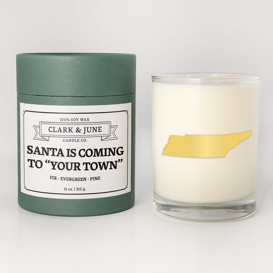 Double wicked soy candle in a 13.5 oz tumbler with the state of Tennesseeprinted in 22k gold foil on the face. Green cylinder packaging with Santa is Coming to "Your Town"on the label. SEO Text – Drinking glass, soy wax candle, Christmas Candle, hand poured, small batch, scented candle, Woman Owned, local candle, Housewarming present, gives back, charity, community candle, becomes a cocktail glass, closing gift. 