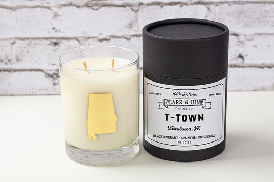 Double wicked soy candle in a 13.5 oz tumbler with the state of Alabama printed in 22k gold foil on the face. Black cylinder packaging with “T-Town” on the label. SEO Text – Drinking glass, soy wax candle, Alabama candle, hand poured, small batch, scented candle, Woman Owned, local candle, Housewarming present, gives back, charity, community candle, becomes a cocktail glass, closing gift. 