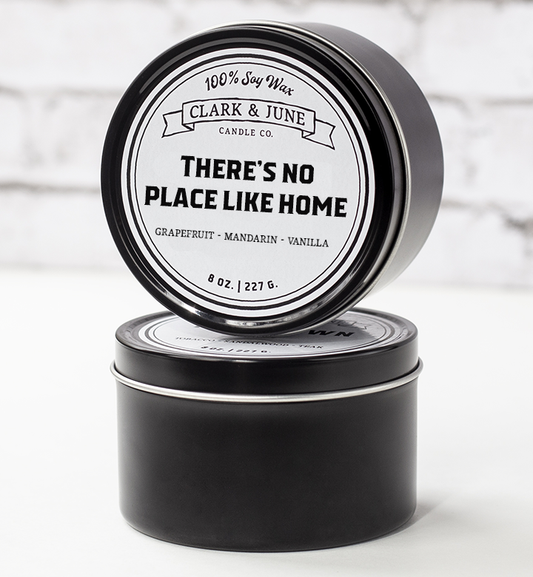 Single wicked 8oz candle in a black finish with "There's No Place Like Home" on the label. SEO Text –soy wax candle, Alabama candle, hand poured, small batch, scented candle, Woman Owned, local candle, Housewarming present, gives back, charity, community candle, closing gift. 